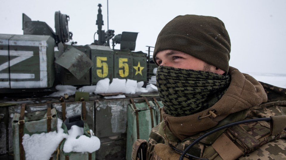 A Ukrainian soldier stands next to a captured "Z" marked tank