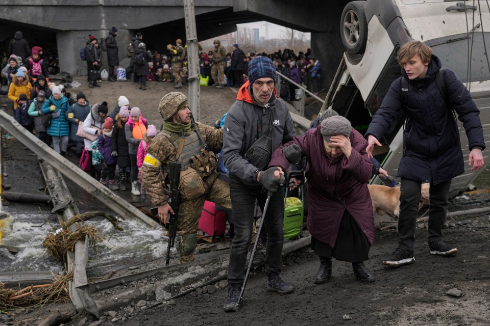 People cross on an improvised path under a bridge that was destroyed by a Russian airstrike in Irpin