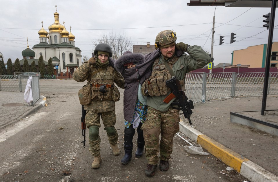 Two soldiers help a woman after the shelling attack near the church