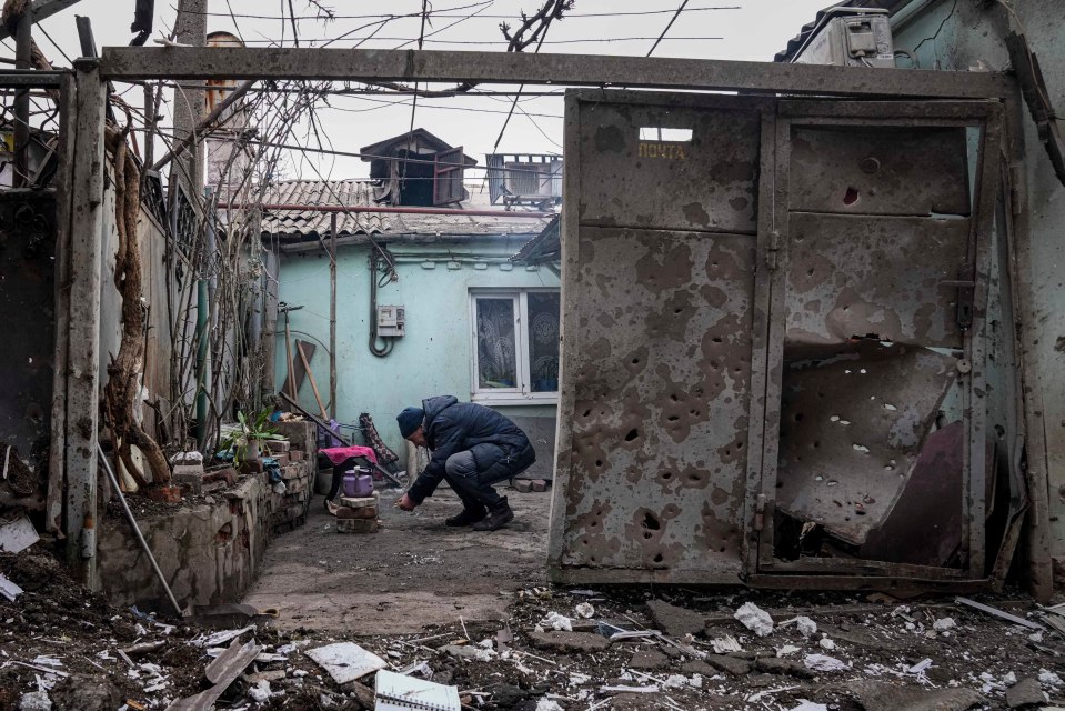 A man lights a fire under the kettle in a yard of a building hit by shelling in Mariupol