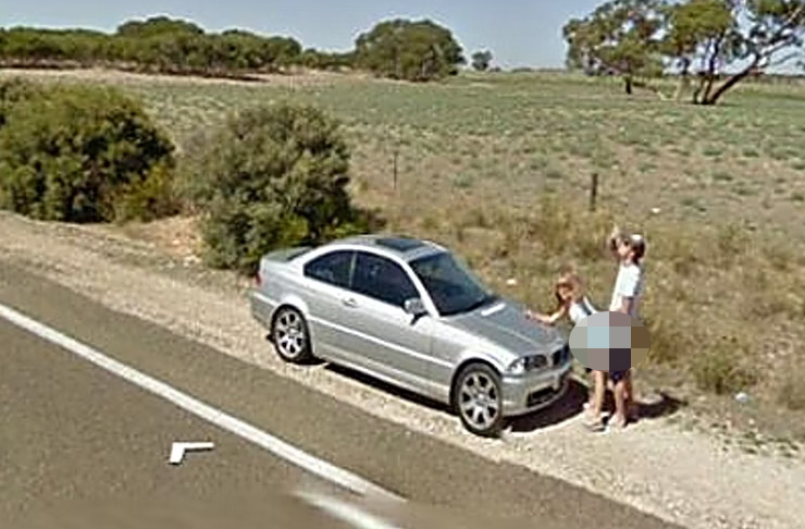 A woman waves at the Google camera while her beer-swigging partner stands behind