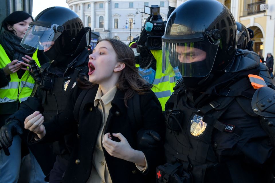 A woman can be seen being dragged away by cops while protesting against the war