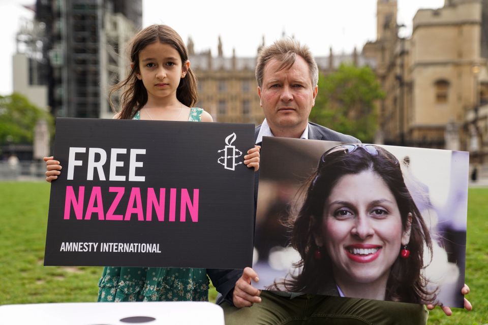 Richard Ratcliffe and his daughter Gabriella holding signs in Parliament Square last year