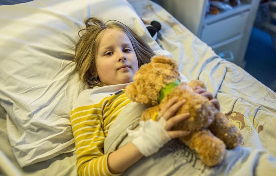 A young girl, who has suffered injuries during the Russian invasion, clutches her teddy while in hospital