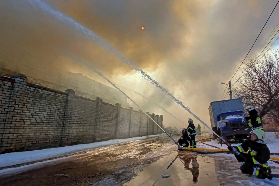 Rescuers work at a site of a warehouse storing products burned after shelling