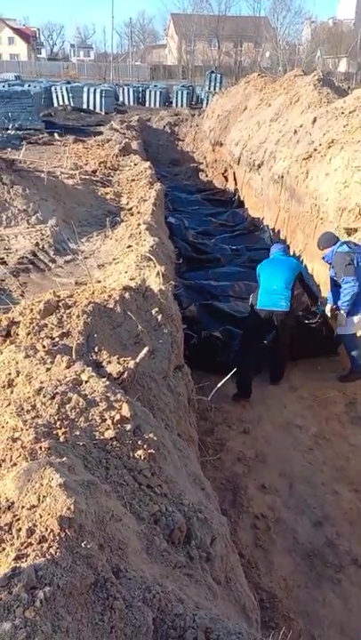 Grieving Ukrainians burying bodies in a mass grave in Bucha