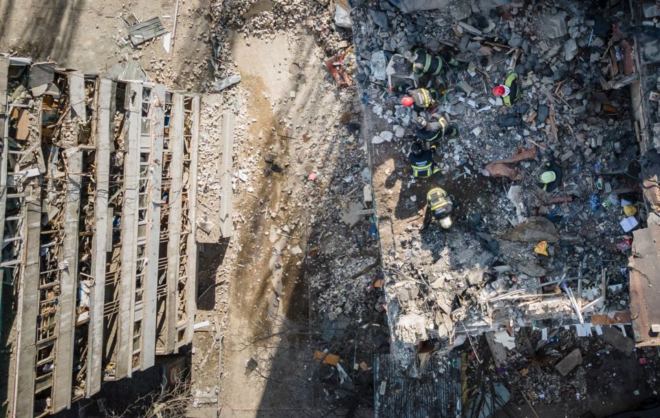 An aerial view shows firemen working in the rubble of a residential building which was hit by the debris from a downed rocket in Kyiv