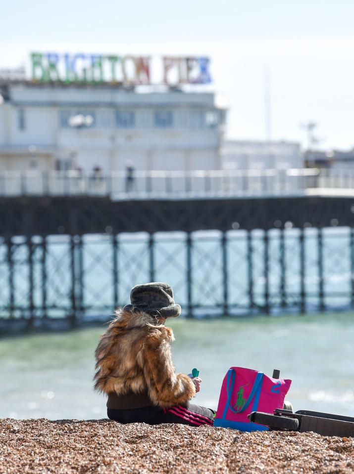 A beachgoer enjoys the sunshine on the pebbles in Brighton