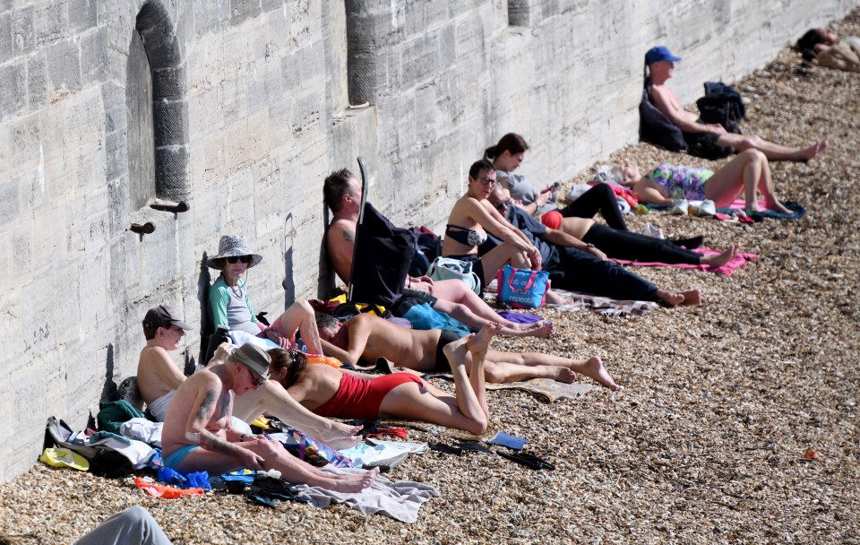 People enjoying the sun on the beach at the Hot Walls in Old Portsmouth, Hampshire