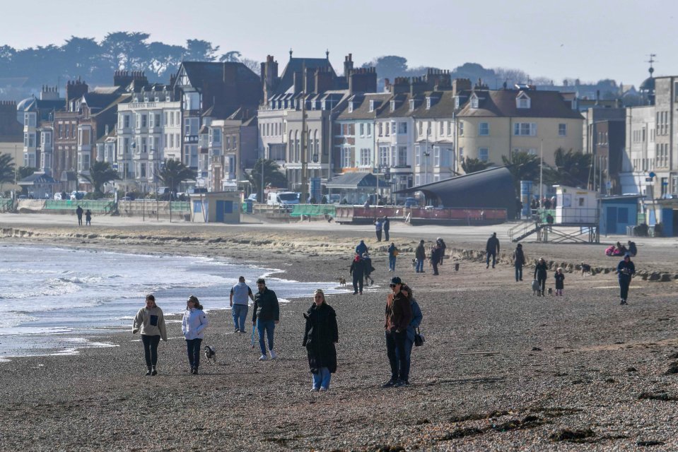 People enjoying a walk on the beach at the seaside resort of Weymouth