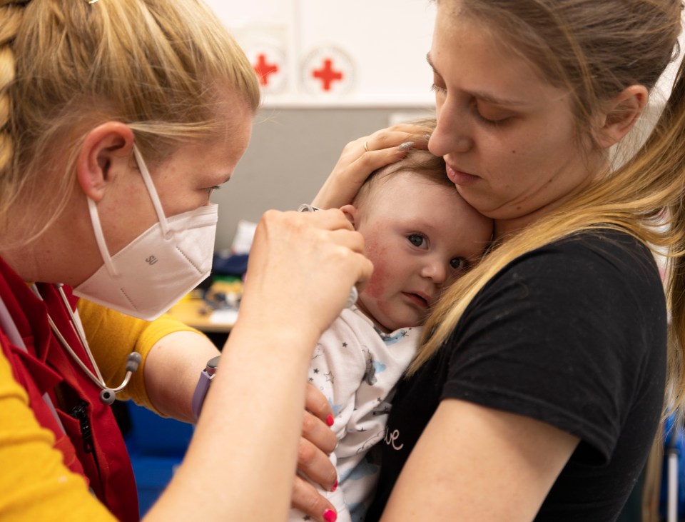 Red Cross doc examines little Alexei, held by mum Tania