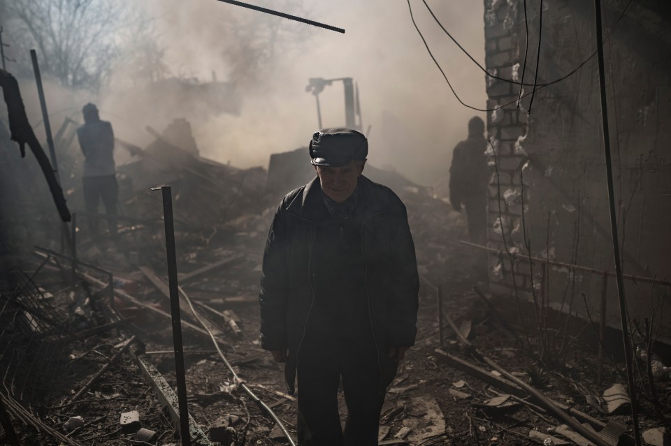 A man walks from a burning house, destroyed after a Russian attack in Kharkiv