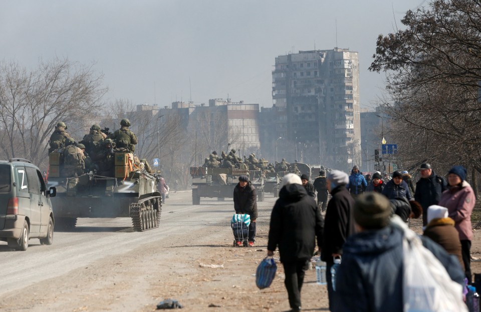 Pro-Russian troops drive armoured vehicles past local residents in the besieged southern port city of Mariupol