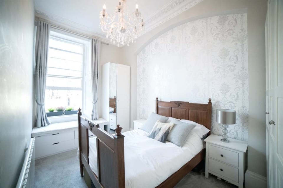 The double bedroom features a chandelier overhead and plenty of room to stand