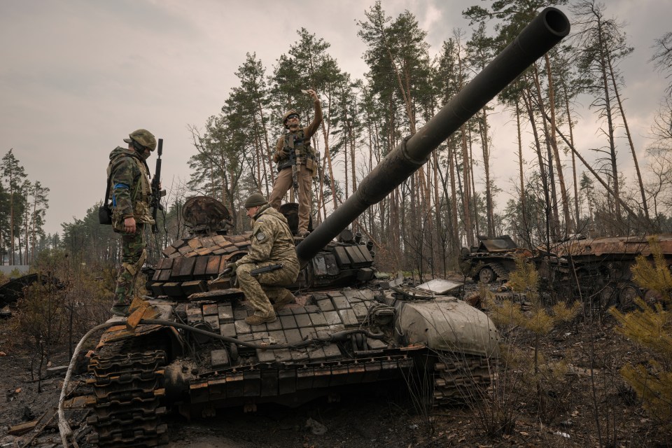 Ukrainian soldiers pose with a captured Russian tank