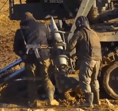 Crew members use a mechanical arm to load the massive shell into the chamber