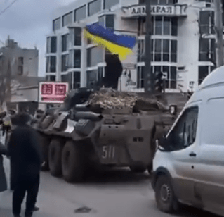 A brave Ukrainian protester climbs atop a Russian armoured vehicle in Kherson