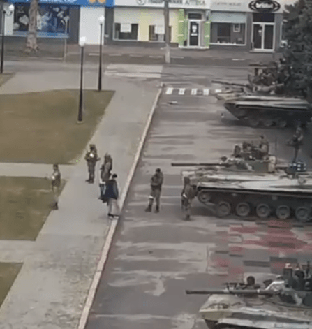 Unimpressed Russian solders and three 'Z' tanks watch the protester