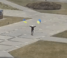 A lone Ukrainian man defiantly waves two national flags at the Russian invaders