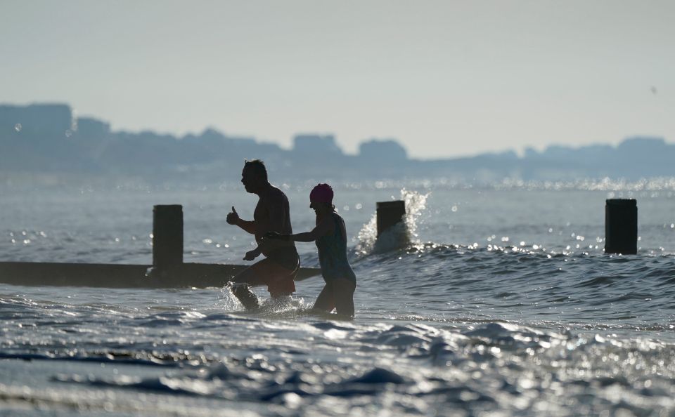 People make their way into the sea after an early morning swim on Boscombe beach in Dorset