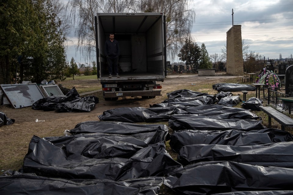 A cemetery worker waits in a truck before colleagues start to load the corpses of civilians killed in Bucha