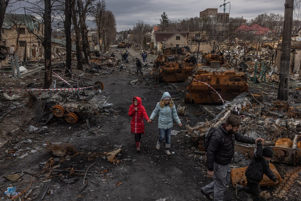 Residents walk amongst the devastation in Bucha