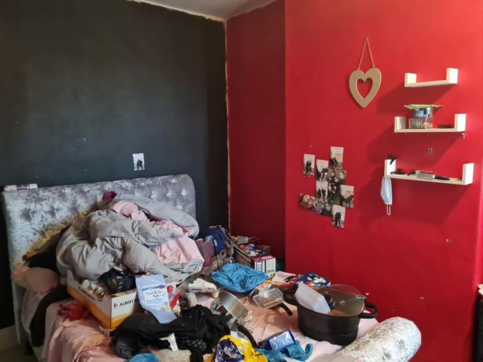 Clutter is piled high on a bed in one of the house's two bedrooms