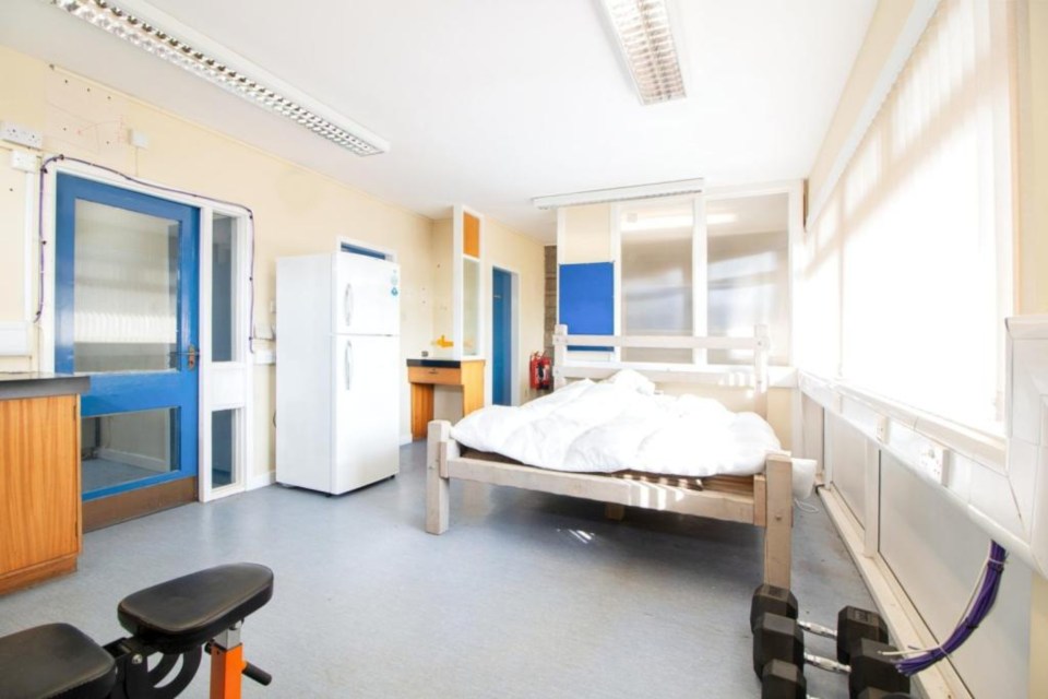 The former police station reception is now a peculiar bedroom with a fridge and weights