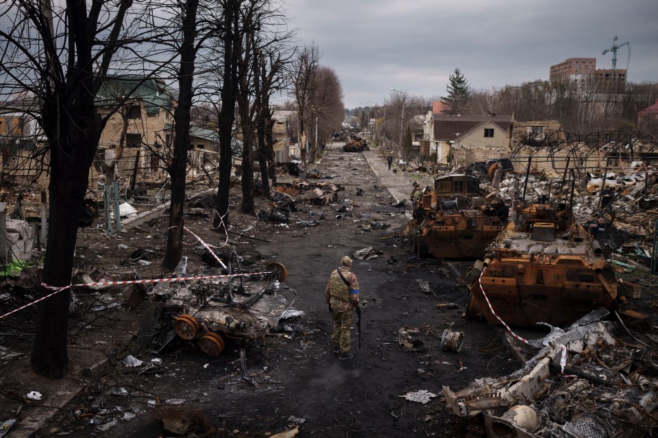 A Ukrainian serviceman walks amid destroyed Russian tanks in Bucha