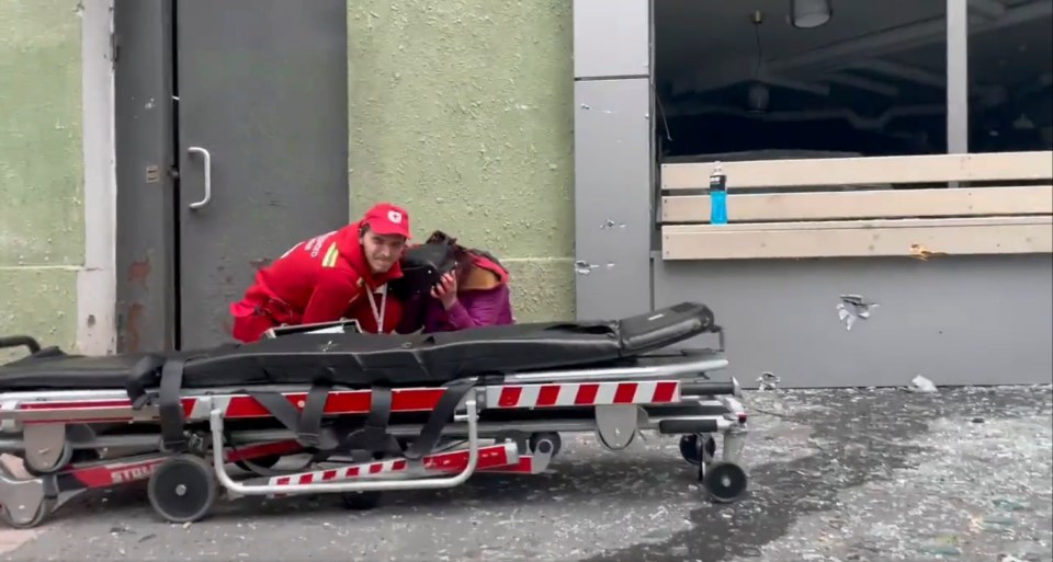 The paramedic can be seen shielding the injured woman from a rocket attack