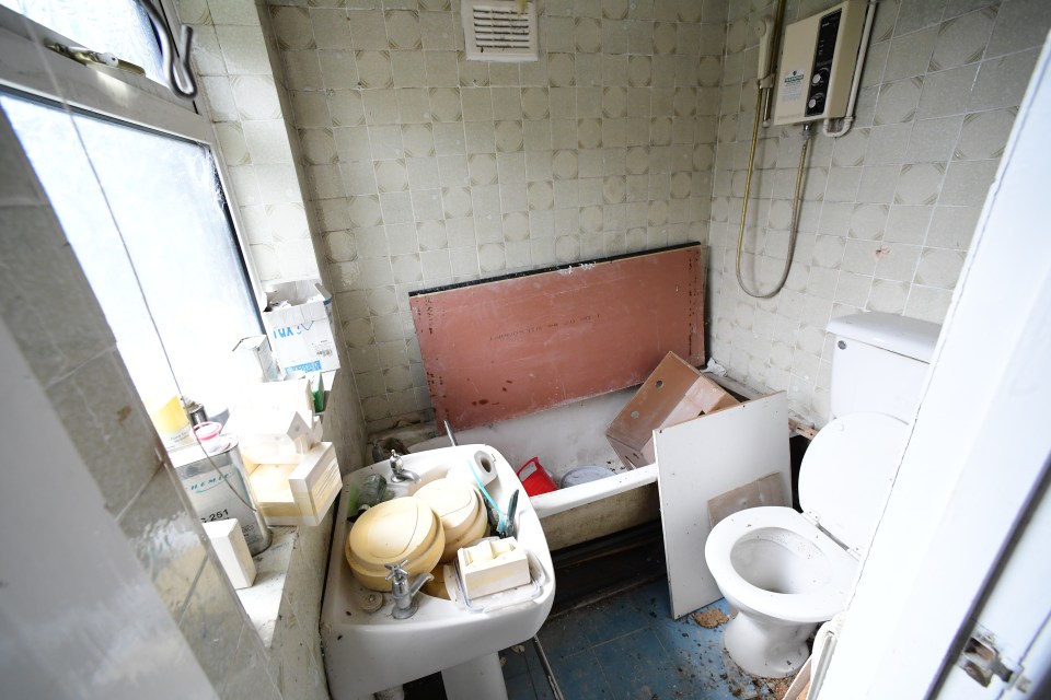 The bathroom is filled with industrial rubbish and the floor littered with rubble