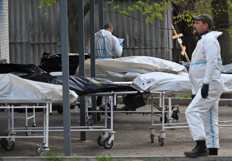 Mortuary workers stand next to stretchers with bags containing bodies of victims in Bucha, northwest of Kyiv