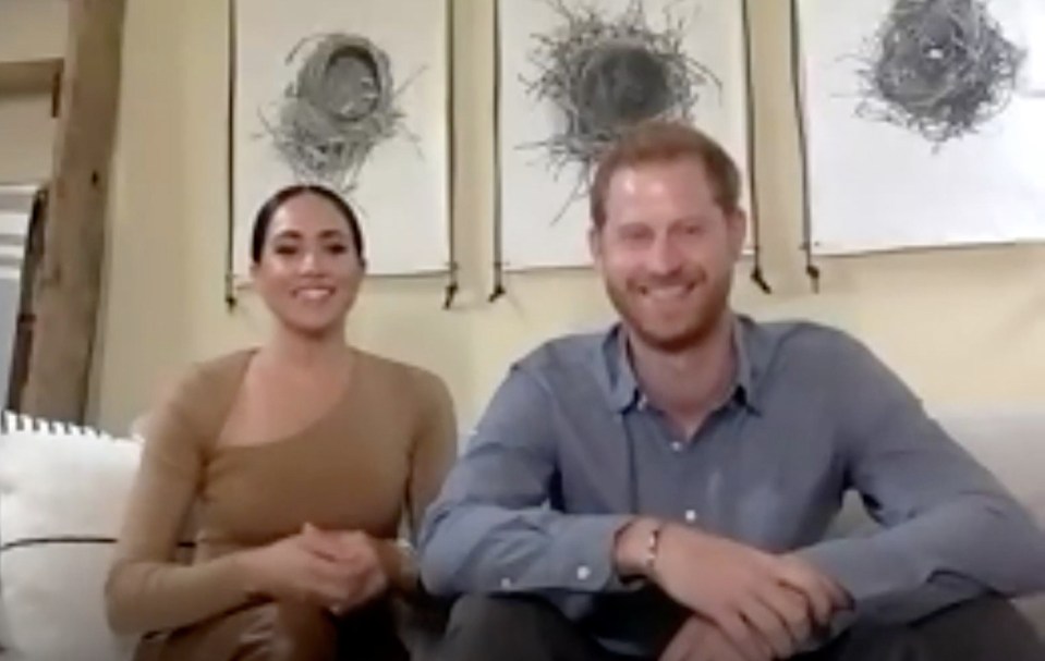 Harry and Meghan sit on their sofa smiling in this clip