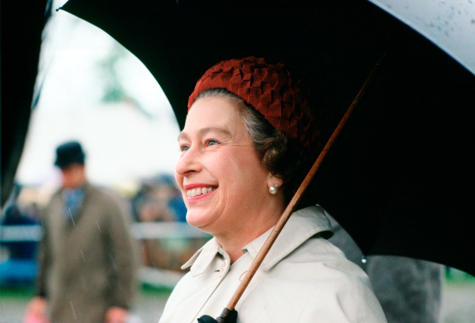 The Queen smiles while sheltering from the rain under an umbrella at Royal Windsor Horse Show in 1978