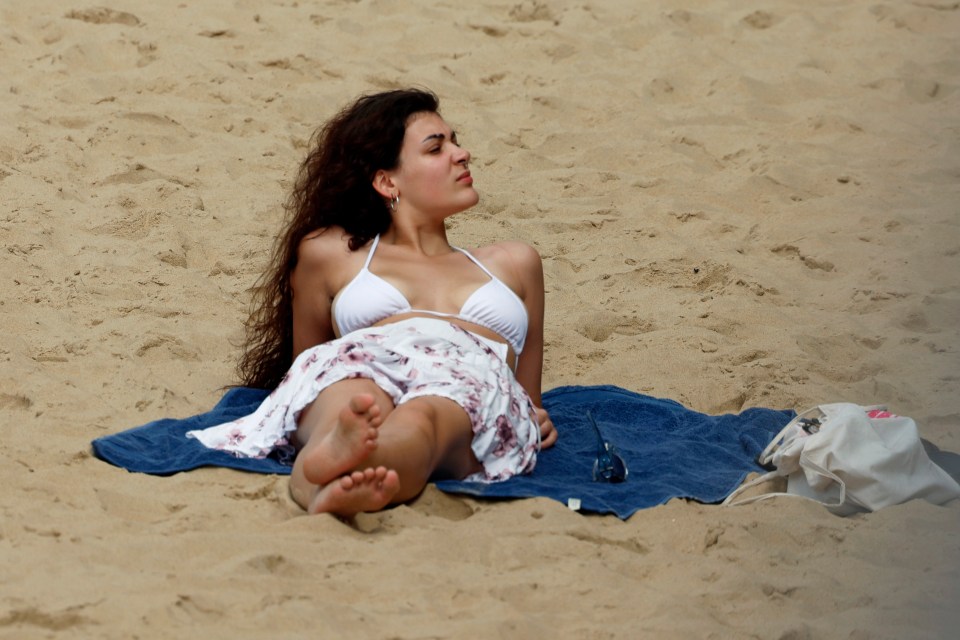 A woman tops up her tan on Bournemouth beach