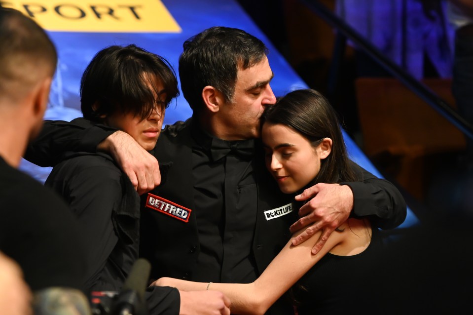 Ronnie hugs his younger son and daughter after his win