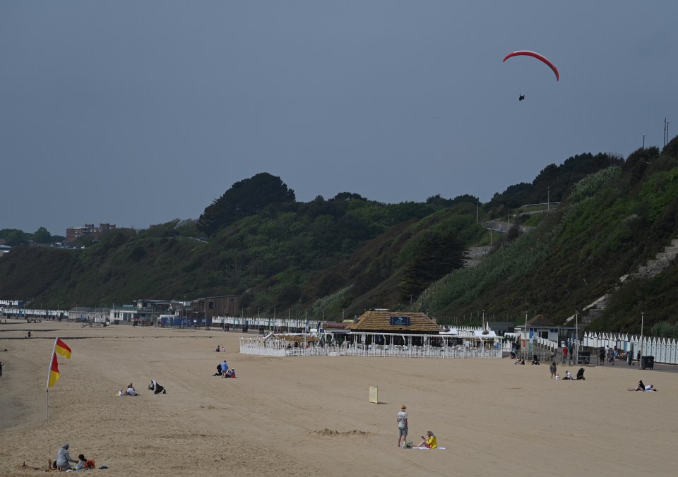 A paraglider soars over sunny Bournemouth beach