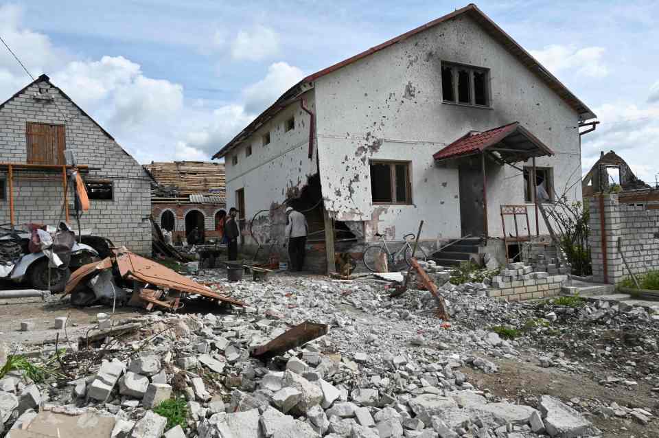 Locals examining the damage of a house in the village of Mala Rogan, Kharkiv