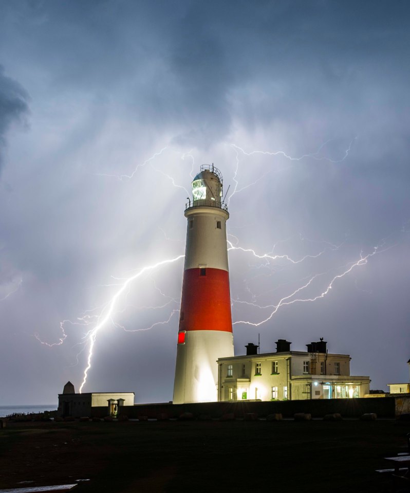 Bolts of lightning illuminate the clouds above the lighthouse at Portland Bill in Dorset