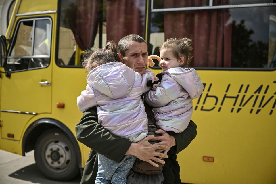 A terrified Ukrainian dad holds onto his two young daughters