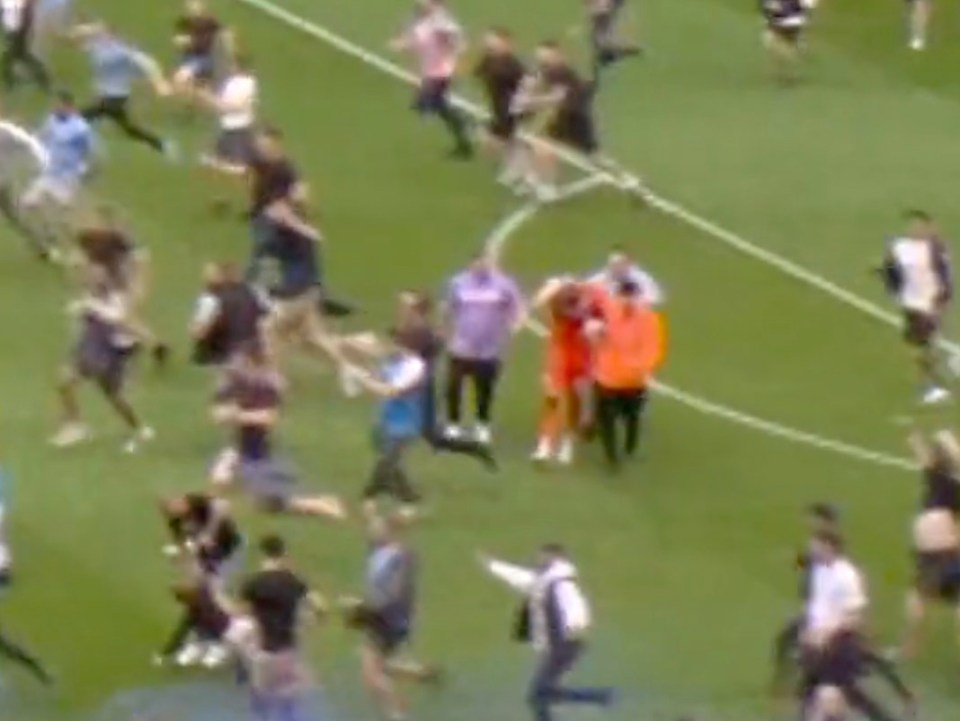 The goalie is helped off the pitch after being deliberately struck at least three times in the chaotic aftermath of City’s title win