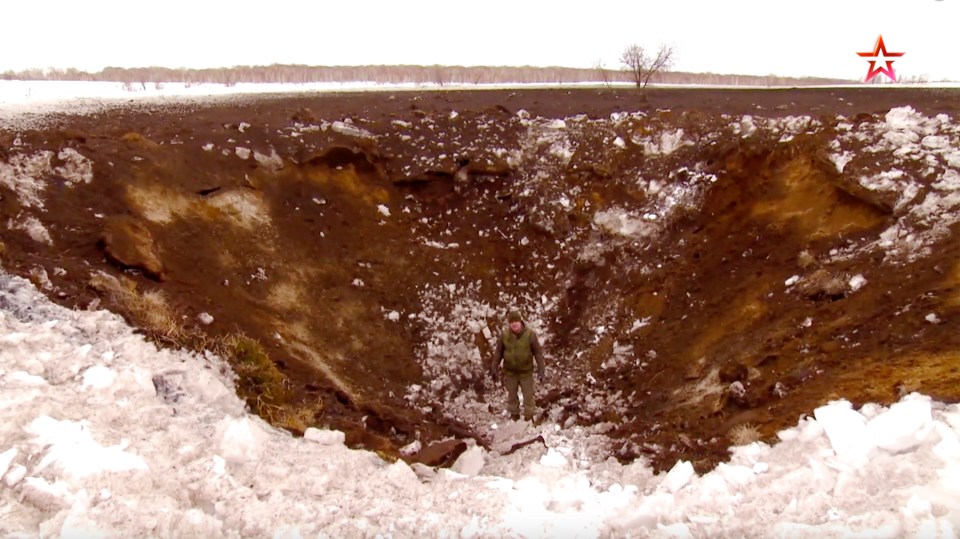 Dmitry Rogozin stands in a 26ft-deep crater he says was made by a Sarmat launched on a firing range without a warhead in April