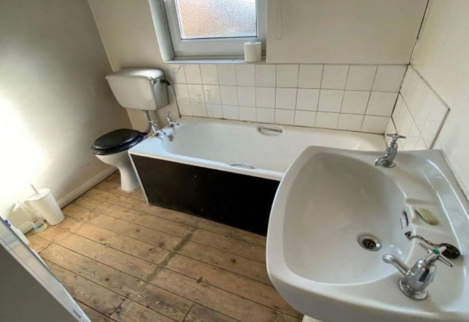 The black and white bathroom has stripped bare floor boards