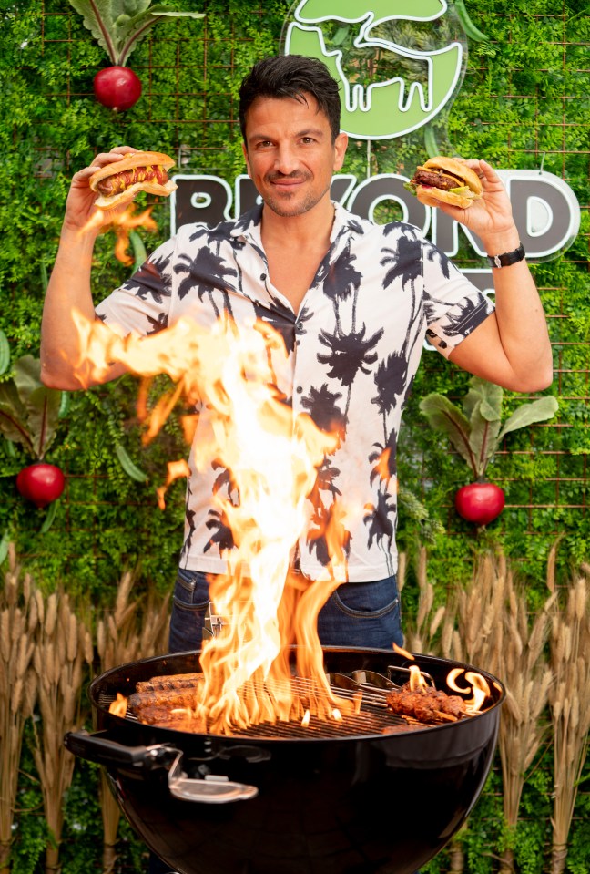 Peter was snapped next to a barbecue cooking plant based burgers and hot dogs