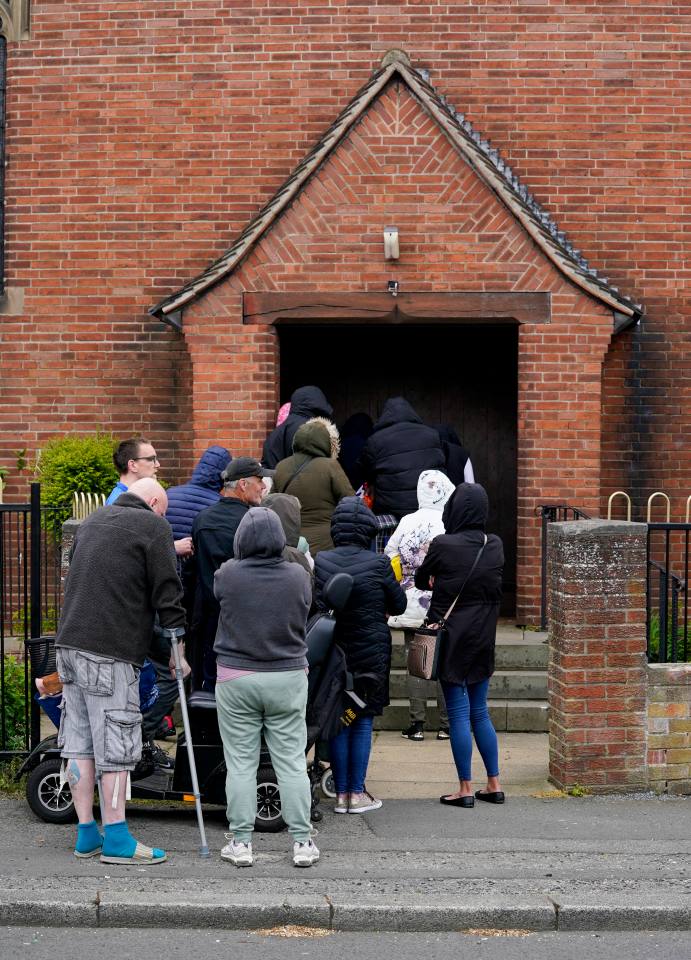 Residents queue outside the church to use the food bank