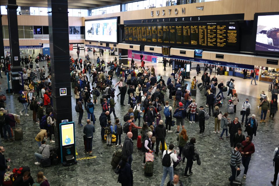 Passengers wait to board trains at Euston Station in London