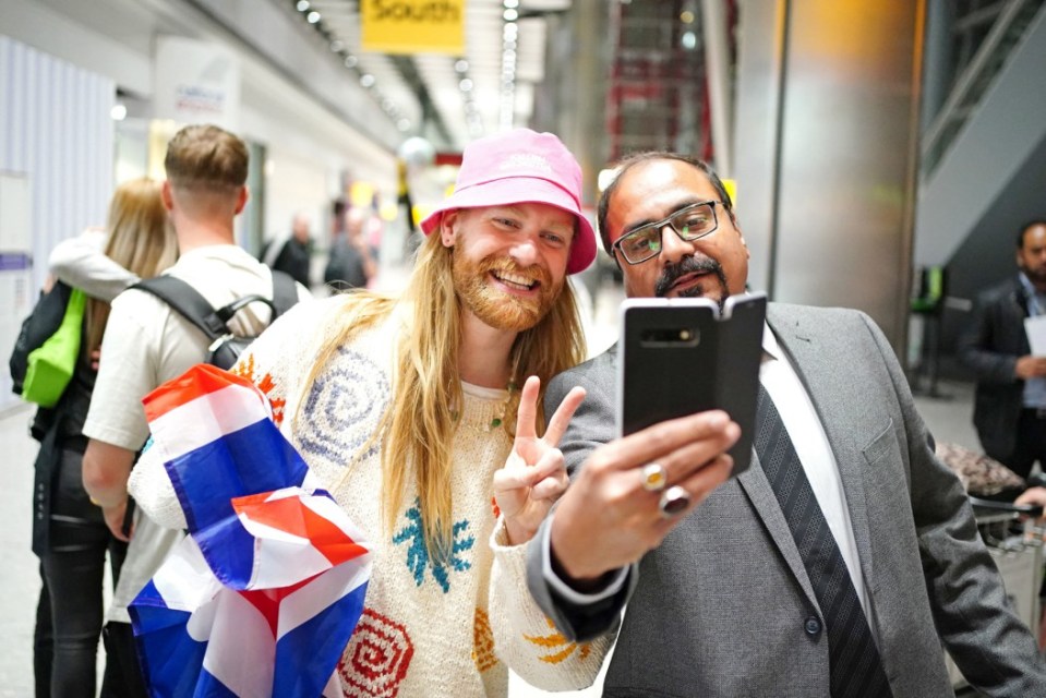 Sam happily posed for snaps with fans as he arrived back in Heathrow