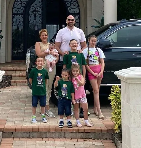 a family is posing for a picture in front of a car .