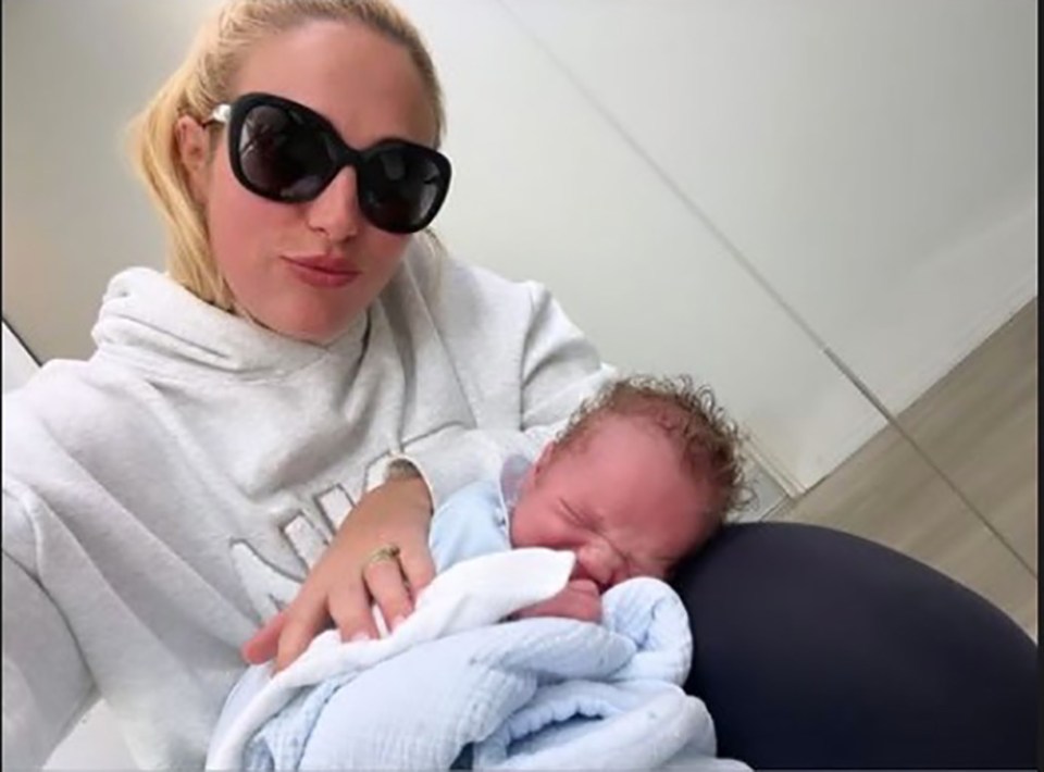 a woman wearing sunglasses is holding a baby in her arms .