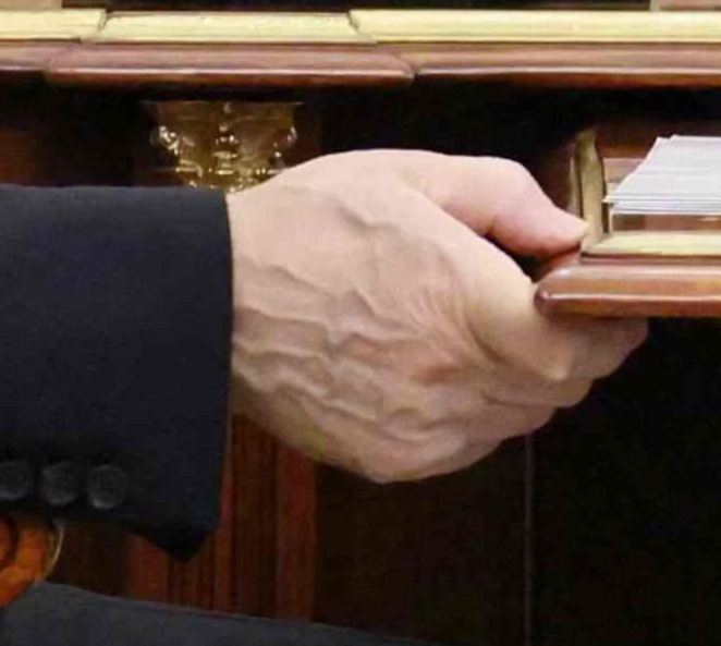 His hands appear to bulging with veins as he grips onto the table